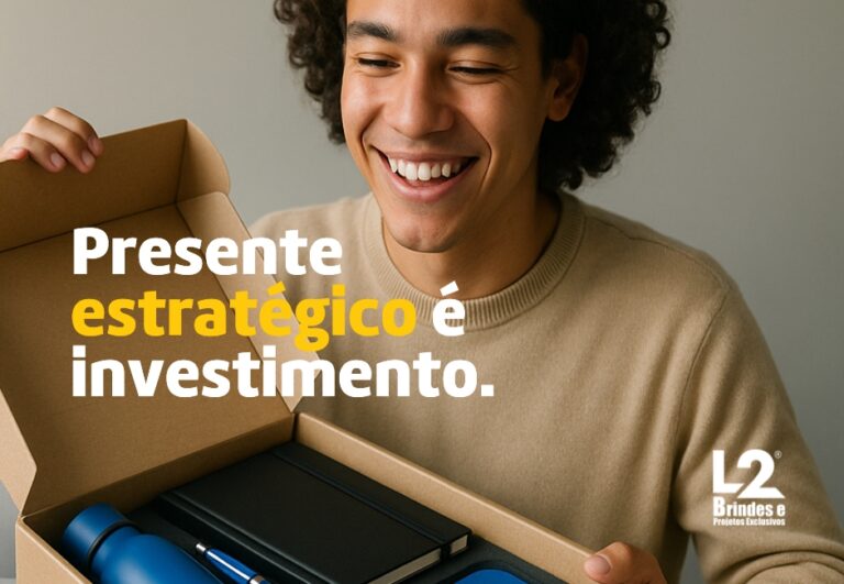 Uma pessoa sorridente abrindo uma caixa de papelão contendo brindes corporativos, incluindo uma garrafa de água azul, uma caneta, um caderno e outros itens. A frase 'Presente estratégico é investimento.' está sobreposta na imagem.