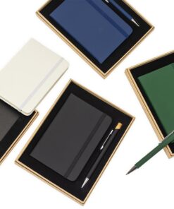 Visão superior de vários kits de brinde executivo com caderno e caneta em cores sortidas (azul, preto, verde, branco), destacando a apresentação do produto.